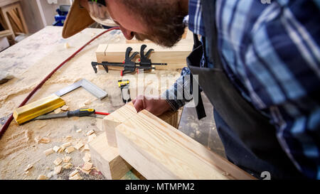 Carpenter in work clothes  doing woodwork in carpentry. small buiness owner work on wood plank in workshop Stock Photo