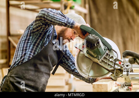 Carpenter work with circular saw for cutting boards, the man sawed bars, construction and home renovation, repair and construction tool Stock Photo