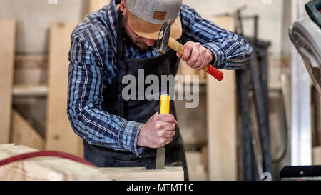 Strong carpenter  in work clothes  carving wood using a woodworking tool, chisel, hands close up, carpentry and craftsmanship concept Stock Photo