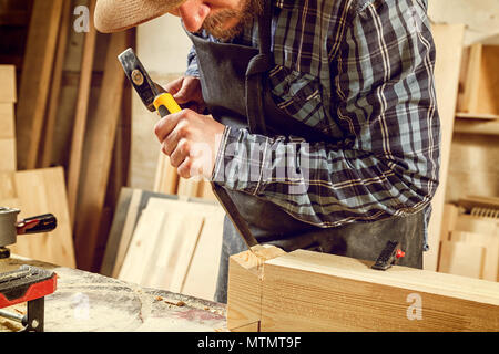 Strong carpenter  in work clothes  carving wood using a woodworking tool, chisel, hands close up, carpentry and craftsmanship concept Stock Photo