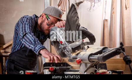 experienced  carpenter using circular saw for cutting wooden boards. Construction details of male worker or handy man with power tools Stock Photo