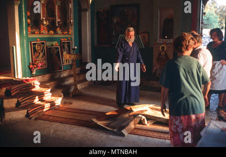 Priest chooses rugs during decoration of church on eve of St. Nikitas, Sellas, Peloponnese, Greece. Stock Photo