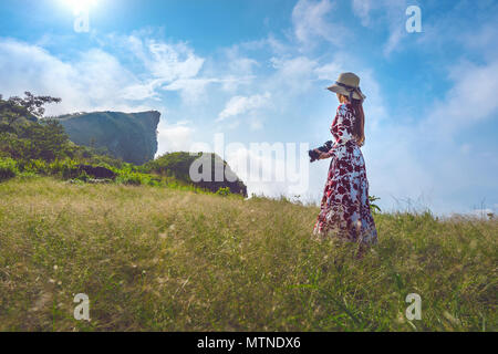 Woman standing on meadow and holding camera at Phu Chi Fa mountains in Chiangrai, Thailand. Travel concept. Vintage tone. Stock Photo