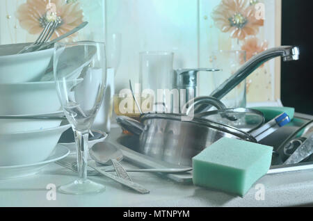 A huge pile of unwashed dishes in the kitchen sink and on the countertop. A lot of utensils and kitchen appliances before washing. The concept of dail Stock Photo