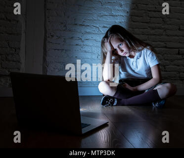 Scared sad girl bullied on line with laptop suffering cyberbullying and harassment feeling desperate and intimidated. Child victim of bullying stalker Stock Photo