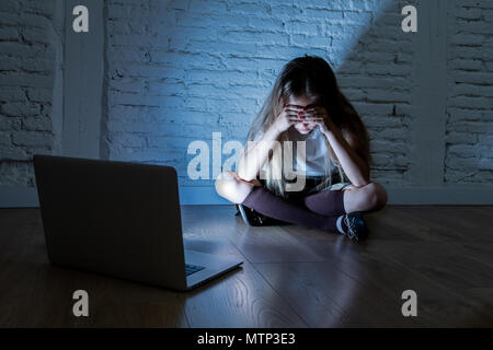 Scared sad girl bullied on line with laptop suffering cyberbullying and harassment feeling desperate and intimidated. Child victim of bullying stalker Stock Photo