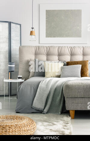 Grey blanket and pillows on comfortable bed in spacious bedroom Stock Photo