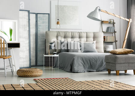 Wicker carpet on the floor in cozy grey bedroom with bed Stock Photo