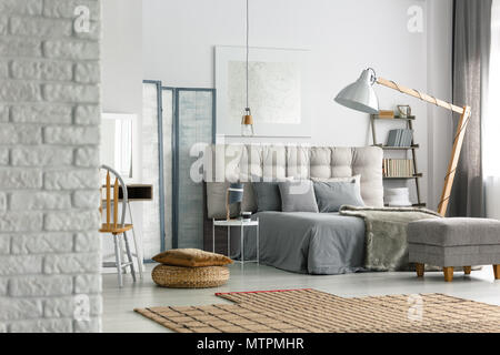 Cozy grey bedroom in modern loft with white brick wall Stock Photo