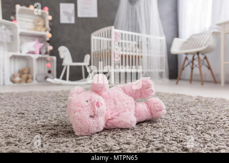 Shot of a pink teddy bear laying on a floor in a modern baby room Stock Photo