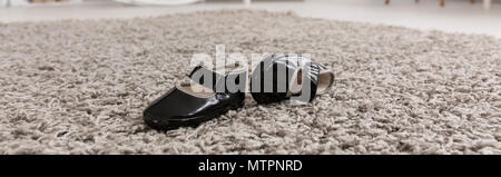 Little black baby shoes lying on a carpet, panorama Stock Photo