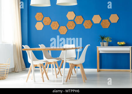 Blue family dining space design idea with white and wooden table, chairs and eco cork wall accessories