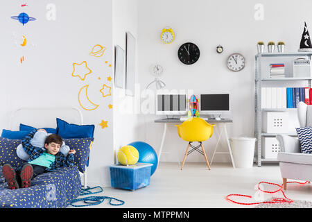 Shot of a little boy laying on a bed in his space inspired bedroom Stock Photo