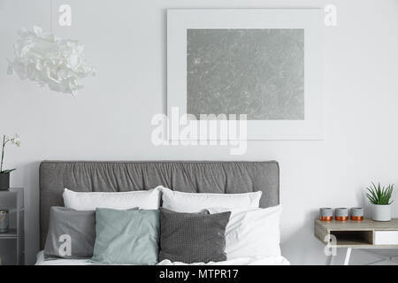 Big modern poster hanging on white wall in stylish bedroom Stock Photo