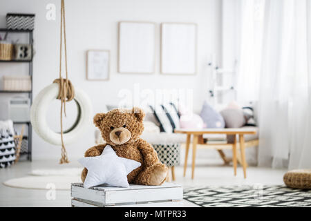 Cute teddy bear toy in white scandinavian playroom with swing Stock Photo