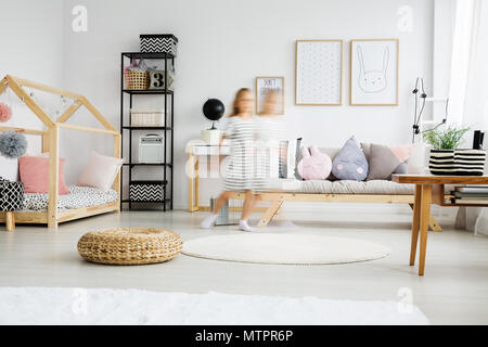 Young child wearing dress running in stylish pastel apartment Stock Photo