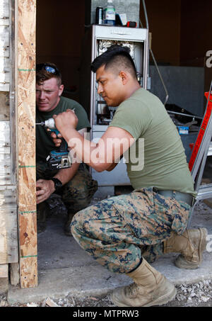 U.S. Marine Lance Cpl. Luis A. Eufraciodolores (right), administrative clerk with Headquarters and Service Company, 6th Engineer Support Battalion, 4th Marine Logistics Group, uses a drill to screw in a door frame as Lance Cpl. Jason P. McWhinnie (left), field radio operator with Engineer Support Company, 6th ESB, 4th MLG, helps hold the frame in place at a construction site during exercise Red Dagger at Fort Indiantown Gap, Pa., May 21, 2018. Exercise Red Dagger is a bilateral training exercise that gives Marines an opportunity to exchange tactics, techniques and procedures as well as build w Stock Photo