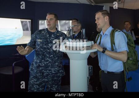 180521-N-DA737-0064 Everett, Wash. (May 21, 2018) Lt. Cmdr. Matt Farrell, the executive officer of Afloat Training Group Pacific Northwest, explains the duties of a conning officer to German Army officer, Maj. Joachim Ruthe, in the navigation, seamanship and ship handling trainer in Naval Station Everett (NSE). Ruthe and his fellow officers are enrolled in the International General/Admiral Staff Officer Course and are touring NSE. (U.S. Navy photo by Mass Communication Specialist 2nd Class Jonathan Jiang/Released) Stock Photo
