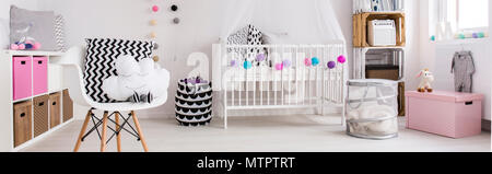 Stylish baby room with white cot, chair, regale and stylish, decorative elements Stock Photo