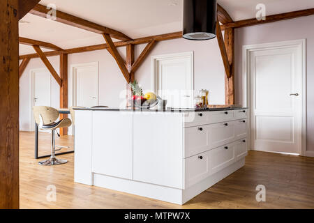 Open space with white kitchen island in room with white doors and wooden construction Stock Photo
