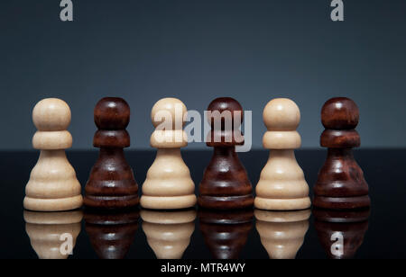 White and black pawns, on dark gray background. Landscape format. Stock Photo