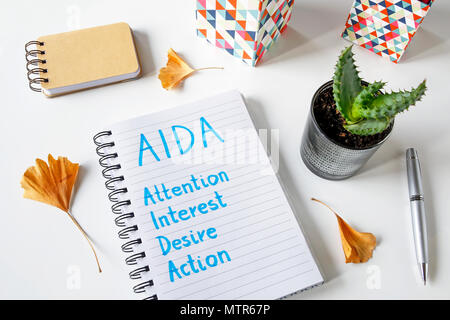 AIDA (Attention Interest Desire Action) written in a notebook on white table Stock Photo