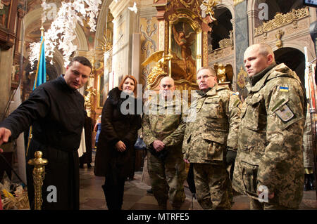 The chaplain for the Ukrainian National Military Academy shows Col. David Jordan, commander of the 45th Infantry Brigade Combat Team, Oklahoma Army National Guard and Joint Multinational Training Group-Ukraine, and Ukrainian Lt. Gen. Pavlo Tkachuk, the chief of the Ukrainian National Military Academy, along with his staff, the soldiers' memorial in Sts. Peter and Paul's Garrison Church in L'viv, Ukraine. Stock Photo