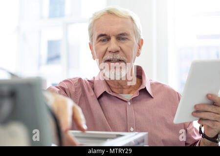 Cheerful senior man checking configurations of 3D printer Stock Photo