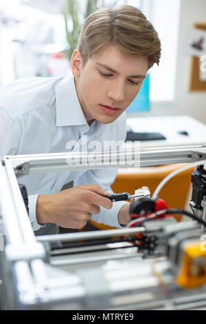 Charming young man using digital caliper to measure printed model Stock Photo