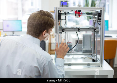 Pleasant young engineer watching 3D printer in action Stock Photo
