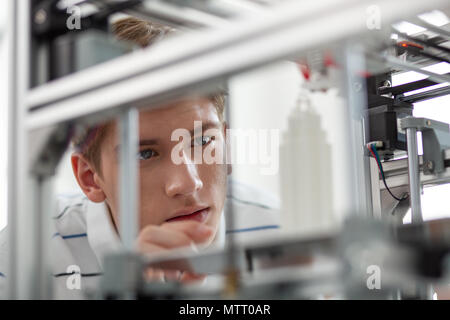 Pleasant young man printing little skyscraper model Stock Photo
