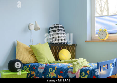 Corner of a teenager's bedroom with a cosy bed covered with colourful bedspread, cushions and soft toys Stock Photo