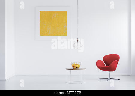 Fresh lemons in metal basket placed on round table in room with yellow poster Stock Photo