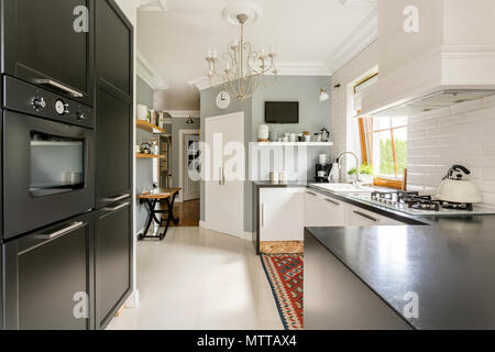 New style spacious kitchen with dark furniture and light tiling Stock Photo