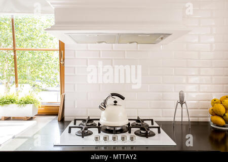 New style kitchen with dark worktop, white gas cooker and decorative brick backsplash Stock Photo