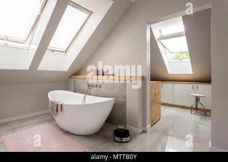 Spacious light attic bathroom with new large bathtub Stock Photo