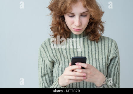 Pretty caucasian girl with red hair sending sms Stock Photo