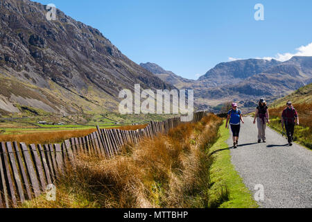 People walking on a country lane with traditional slate fence in Nant Ffrancon valley in Snowdonia National Park in summer. Ogwen Gwynedd Wales UK Stock Photo