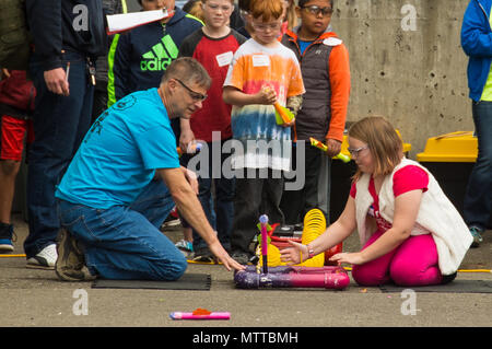 Puget Sound Naval Shipyard and Intermediate Maintenance Facility is a United States Navy shipyard in Bremerton, Washington, providing maintenance and modernization for naval vessels. On May 24, 2018, a shipyard employee assisted students from Armin Jahr Elementary School in launching paper rockets using compressed air during a STEM day at the Puget Sound Navy Museum. The archival image records the educational outreach activity. Stock Photo