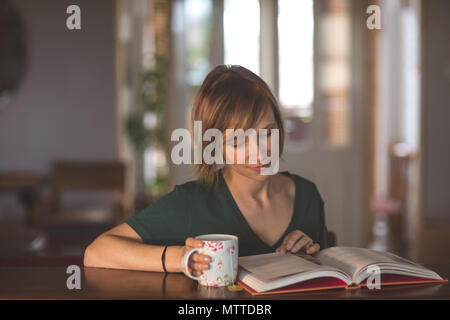 Beautiful woman reading book while having coffee Stock Photo