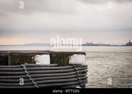 The statue of liberty off in the distance in the Hudson River as seen from Pier 25 of Hudson River Park in New York City. Stock Photo