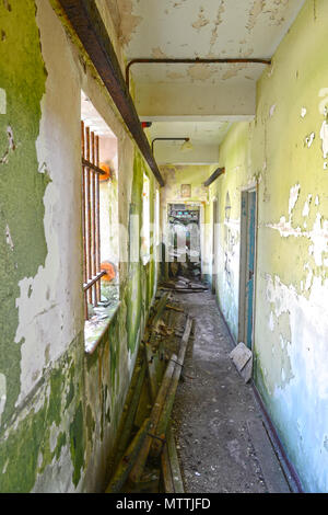 Inside an old derelict vandalised building with paint peeling graffiti and total desolation with broken glass windows and no doors Stock Photo