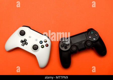Black & White joysticks on orange textured background. Computer gaming competition videogame control confrontation concept Stock Photo