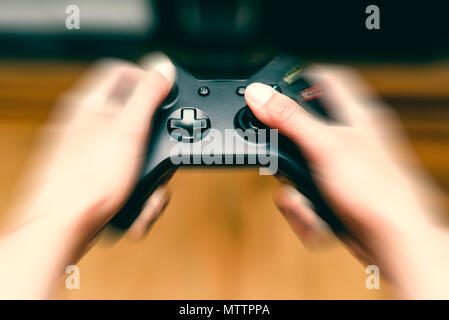 Close-up blur hands with movement pressing and holding a modern game console joystick Stock Photo