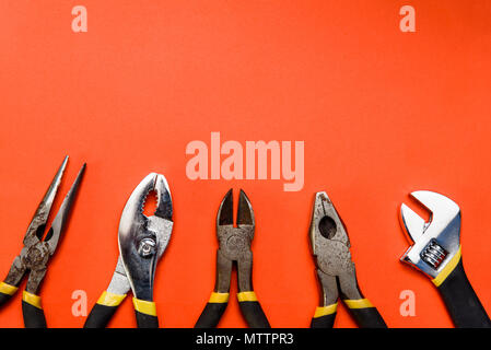 Various Used Pliers Tools on a orange textured background with space for text Stock Photo