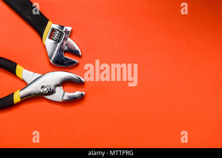 Various Used Pliers Tools on a orange textured background with space for text Stock Photo