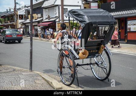 Kyoto, Japan - 24 July 2016. Street in Kyoto on a summer day in July, a man pulling a rickshaw. Stock Photo