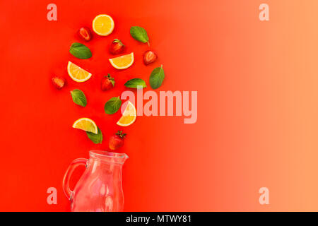 Flat lay Strawberry lemonade ingredients - lemon slices, mint leaves and strawberries falling in a jar on gradient red background. Summer drinks. Mini Stock Photo