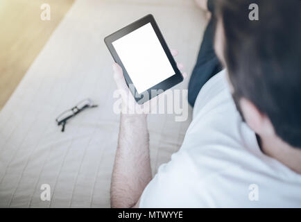 man relaxing on couch using e-book reader or tablet computer Stock Photo