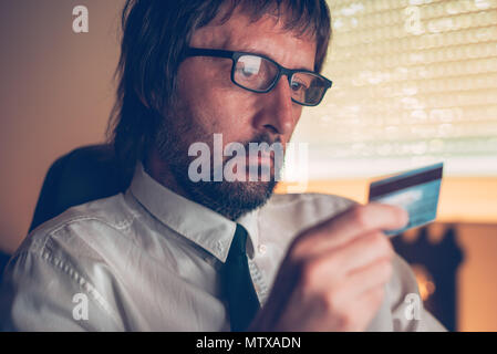 Businessman shopping online and completing internet purchase with debit payment card in dark office interior, selective focus Stock Photo